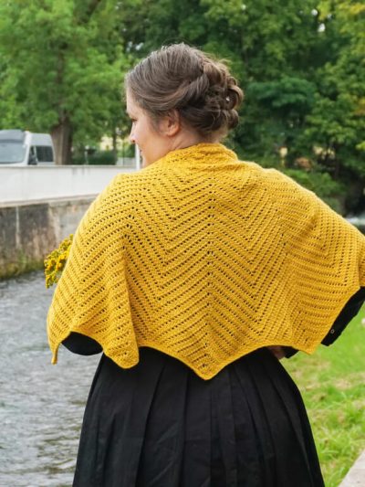 Back view of yellow Tunisian crochet shawl with chevrons that grow from the top middle, making scallops pointy on the edge.