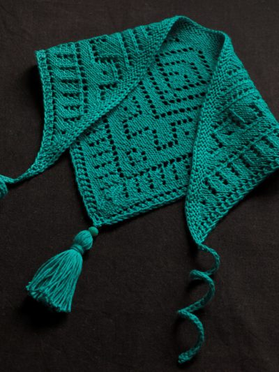 Sample for the Caribbean Sea bandana knitting pattern, worked in turquoise size 2 cotton yarn, with attached tassels and swirly ties.